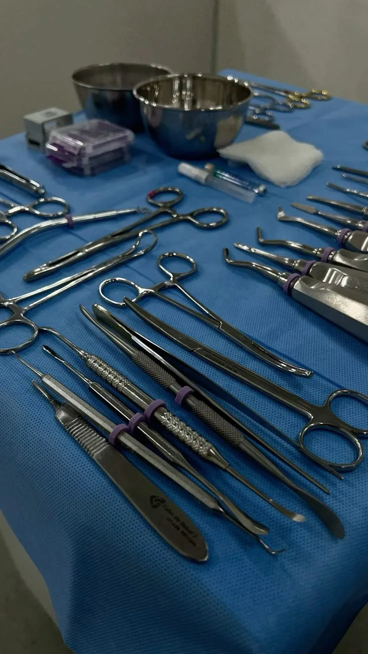 Instrumental cirúrgico esterilizado organizado sobre campo azul: pinças, tesouras, alavancas e cubas de inox